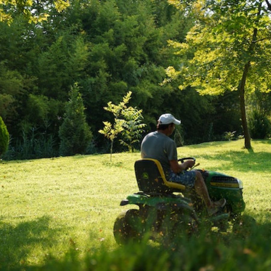 a man cutting grass on a riding lawn mower