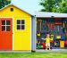 A family enjoying their transformed backyard with a colorful playhouse and attached storage shed. The playhouse is lively and inviting for children, while the storage part is practical and organized.