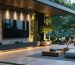 Luxury patio with a retractable TV system, partially concealed within a modern cabinet, set against a backdrop of greenery during an evening movie night.