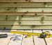 Depiction of a robust wooden shed foundation made of pressure-treated lumber with tools like a level and measuring tape scattered around, illustrating construction strength and durability.