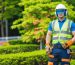 A professional landscaper wearing full personal protective equipment, including safety glasses, work gloves, and a high-visibility vest, demonstrating best practices for safe landscaping work.