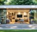 "A modern backyard shed with large windows and a sleek design, surrounded by a landscaped garden. The interior is visible, showcasing an organized multi-purpose space combining a home office, workshop, and relaxation area with abundant natural light and efficient storage solutions."