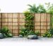 A backyard featuring a 6-foot privacy screen constructed from various cost-effective materials, including bamboo rolls, reed fencing, and lattice panels, providing both privacy and aesthetic appeal.