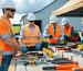 Workers in safety gear demonstrating proper outdoor workspace safety practices with organized tool storage and clearly marked pathways in a well-maintained outdoor environment.