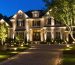 Professional lighting contractor installing LED landscape lights at night, transforming home's exterior with elegant and secure illumination.