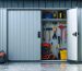 A sturdy, partially open metal storage shed door with an advanced lock system, showcasing organized tools and equipment inside. Light rain droplets illustrate weather resistance, enhancing the sense of security and durability.