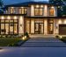 "A modern home exterior elegantly lit by Z-Wave outdoor lights, including security floodlights, pathway lights, and porch lanterns, demonstrating the integration and automation capabilities of smart lighting technology."