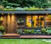 Eco-friendly backyard shed constructed from reclaimed wood, featuring a green roof with succulents and large windows for natural light. The shed includes a rainwater collection system integrated with the roof, set amidst a vibrant garden setting.
