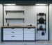 Interior view of an 8x12 shed transformed into a high-tech workspace, featuring automated shelving systems, motion-activated LED lights, and a fold-down desk with charging stations.