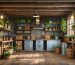 Interior of a rustic shed featuring exposed wooden beams, reclaimed barn wood walls, vintage lighting, and rustic storage solutions with wooden crates and woven baskets.
