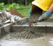 Construction worker pouring eco-friendly, low-carbon concrete into a shed foundation, with recycled aggregates and carbon-capturing materials featured, highlighting green building practices.