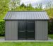 "Garden shed fitted with a new metal roof, surrounded by green foliage under a bright sky."