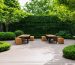 "Serene outdoor workspace with dense hedgerows and mature trees serving as natural sound barriers, surrounded by lush greenery."