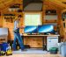 A remodeled shed turned into a tranquil workspace with evident soundproofing elements like mass-loaded vinyl and acoustic foam, depicted mid-application by a person sealing gaps with acoustic caulk.