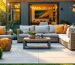 Outdoor living room beside a modern backyard shed with teak sofa, wicker lounge chair, lift-top aluminum coffee table, and a storage bench, photographed at golden hour.