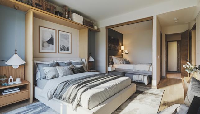 The image shows a modern Winnipeg apartment bedroom featuring a space-saving Murphy bed paired with a plush foam mattress and minimalist bedding. Natural wood finishes and handcrafted furniture elements create a calm, functional atmosphere designed for efficient urban living.