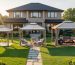 Three differently sized gazebos set across a suburban backyard next to a house, each with simple patio furniture underneath, showing scale, clearance, and walking space in warm evening light.
