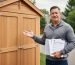 Homeowner reviewing shed warranty paperwork next to a newly installed storage shed on a residential property.