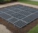 Interlocking foundation grid panels for a 10x12 metal shed laid on prepared, level backyard ground, ready for shed placement.