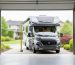 “Measuring tape and an RV positioned inside an open garage to illustrate planning the right RV garage size and clearances.”